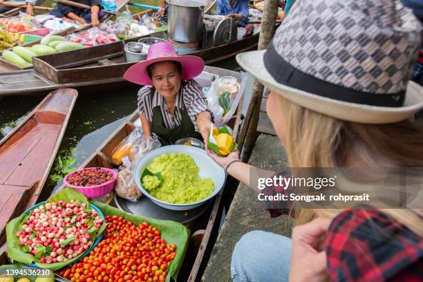 tourists take a walk, buy food, take photos. tourists take photos at a floating market in thailand. - marché flottant photos et images de collection