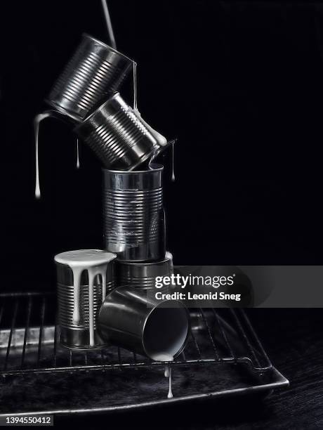 balancing tin cans with dripping condensed milk on black background - open toe bildbanksfoton och bilder