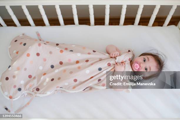 baby in sleeping bag laying down in a crib - saco de dormir fotografías e imágenes de stock