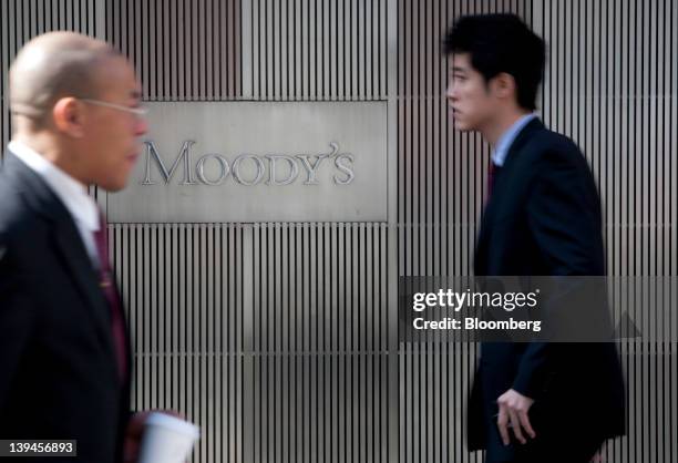 Pedestrians walk past the Moody's Investors Service Inc. Logo displayed outside of the company's headquarters in New York, U.S., on Tuesday, Feb. 21,...