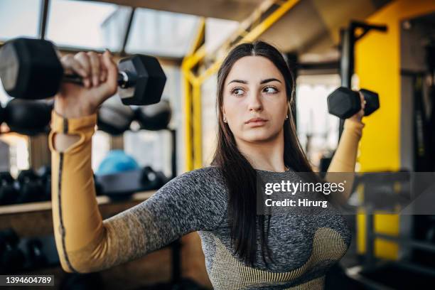 young woman training with dumbbells - women's weightlifting stock pictures, royalty-free photos & images