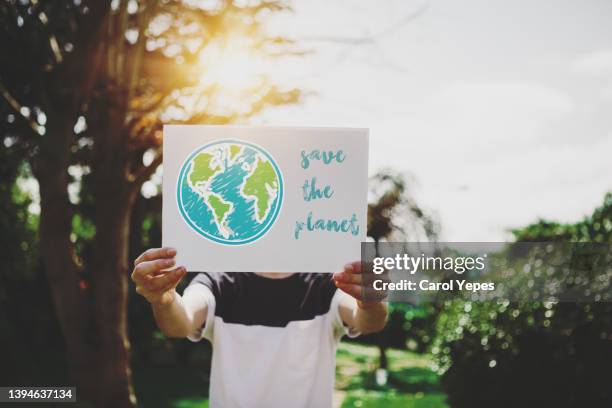 little boy l is holding a cardboard sign that says save the planet. - fight for 15 protest stock pictures, royalty-free photos & images