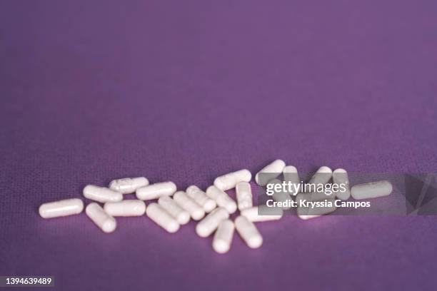 handful of vitamin capsules spilling out of a medicine bottle - prescription drugs dangers stock pictures, royalty-free photos & images
