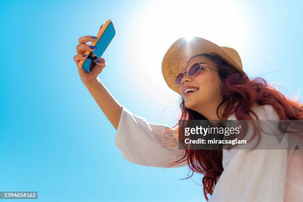 smiling pretty young girl taking selfie on the beach. - rood gekleurd haar stockfoto's en -beelden