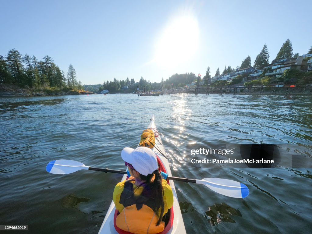 Young Eurasian Woman Enjoying View While Kayaking Along Residential Coastline