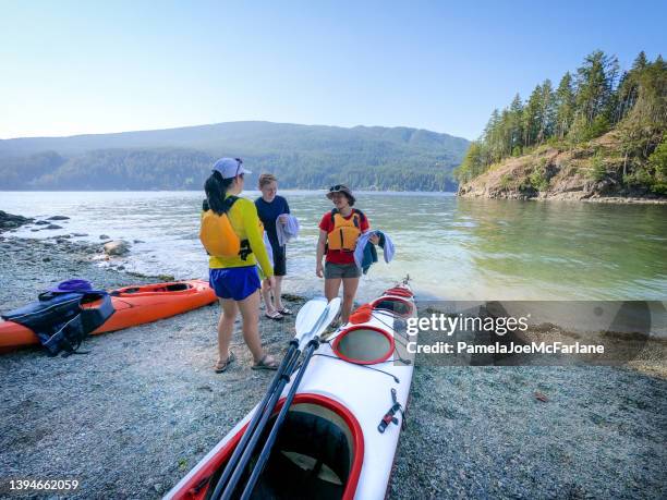 multi-race young adult friends on beach preparing to go kayaking - canadian pacific women stock pictures, royalty-free photos & images