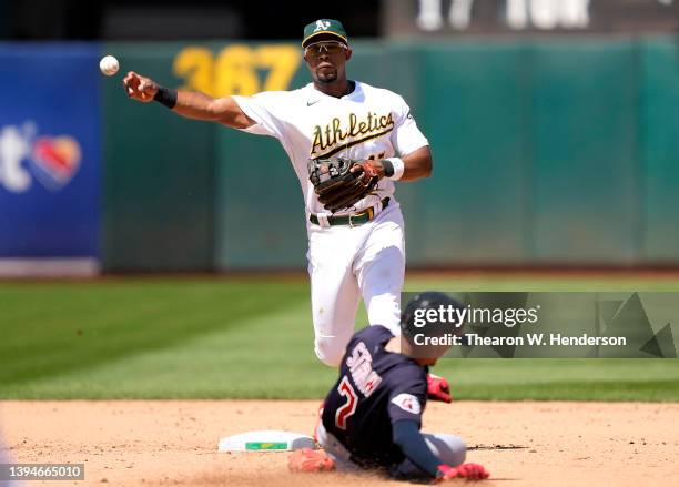 Elvis Andrus of the Oakland Athletics completes the double-play throwing to first base over the top of Myles Straw of the Cleveland Guardians in the...