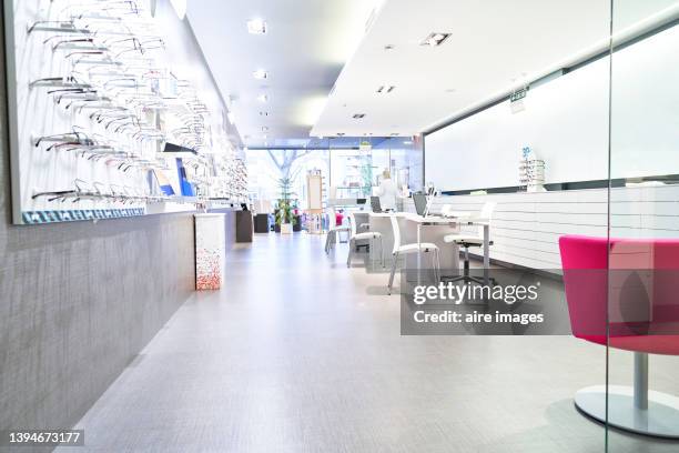 prescription eyeglass frames numbered in optical store, female optometrist in the background . eyeglasses store, vision correction. - furniture showroom stock pictures, royalty-free photos & images