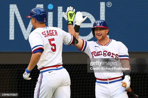 Corey Seager of the Texas Rangers is greeted by Kole Calhoun after Seager hit a solo home run against the Atlanta Braves in the first inning at Globe...
