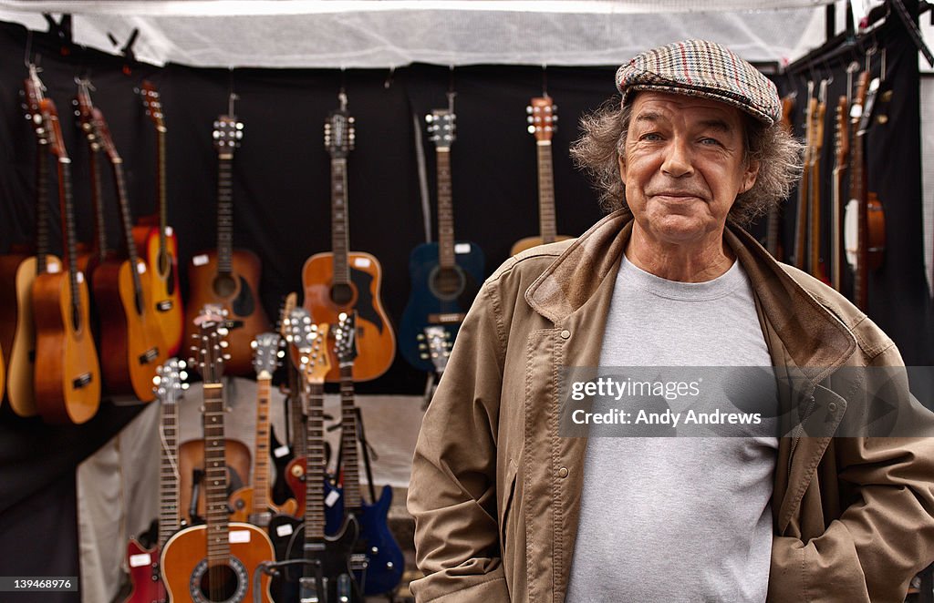 Portrait of a guitar seller in front of his stall