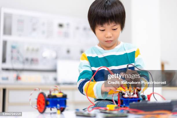 young asian kid coding and building robot car with electronic board in stem class, steam, mathematics engineering science technology computer code in robotics for kids concept. - games workshop stock pictures, royalty-free photos & images