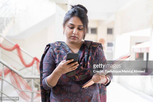 young indian woman using a mobile/digital tablet in the campus of an educational institute located in guwahati, assam. - india phone professional stock pictures, royalty-free photos & images
