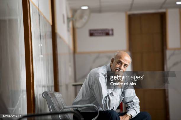 man sitting in hospital corridor - outpatient care stock pictures, royalty-free photos & images
