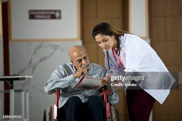 doctor with disabled man on wheelchair examining test results at hospital - medical record stock pictures, royalty-free photos & images