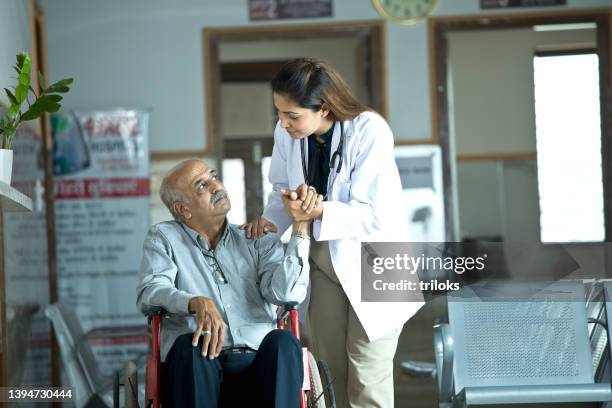 female doctor consoling worried senior man sitting on wheelchair at hospital - touch sensitive stock pictures, royalty-free photos & images