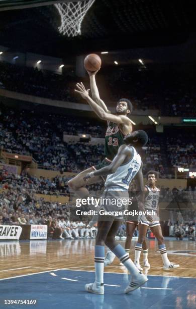 Center Kareem Abdul-Jabbar of the Milwaukee Bucks shoots the ball as forward Bob McAdoo and guard Randy Smith of the Buffalo Braves look on during a...