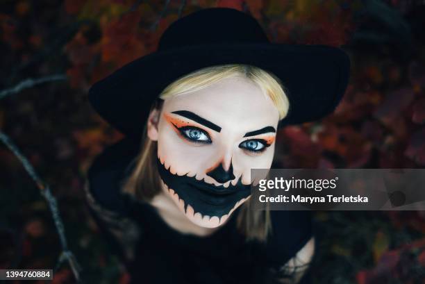 a girl in a hat with a beautiful halloween make-up smiles. halloween. autumn forest. - girl full moon stockfoto's en -beelden