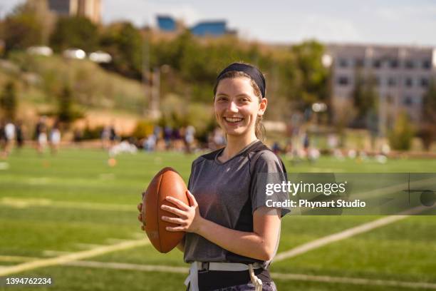 portrait of a young woman holding a football on a field - afl woman stock pictures, royalty-free photos & images