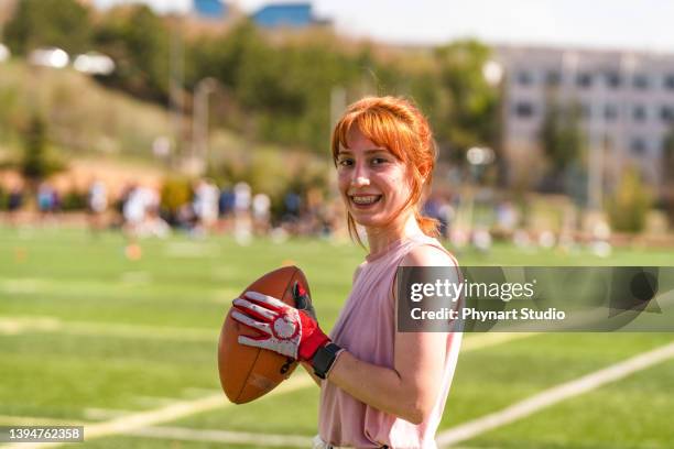 portrait of a young woman holding a football on a field - match sport stockfoto's en -beelden