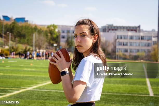 portrait of a young woman holding a football on a field - afl woman stock pictures, royalty-free photos & images