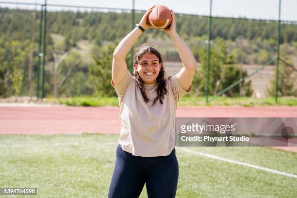portrait of a young woman holding a football on a field - chubby arab stock pictures, royalty-free photos & images