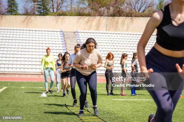 athleten laufen leiterbohrer auf einem grünen rasenplatz - girls on train track stock-fotos und bilder
