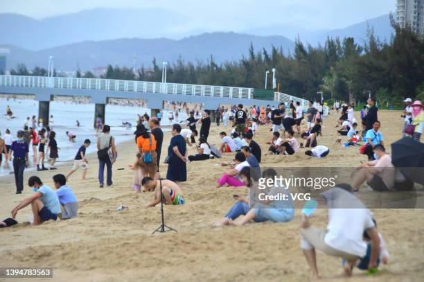 Tourists sit on the beach at Sanya Bay during the May Day holiday on May 1, 2022 in Sanya, Hainan Province of China.