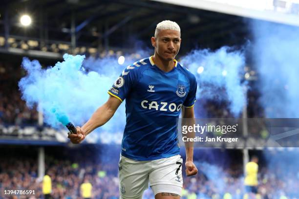 Richarlison of Everton celebrates with a flare after scoring their team's first goal during the Premier League match between Everton and Chelsea at...