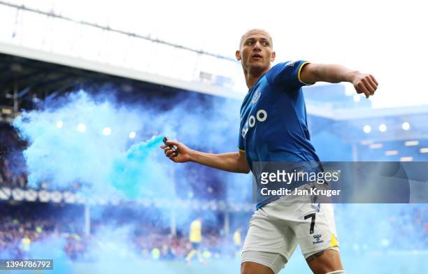 Richarlison of Everton celebrates with a flare after scoring their team's first goal during the Premier League match between Everton and Chelsea at...