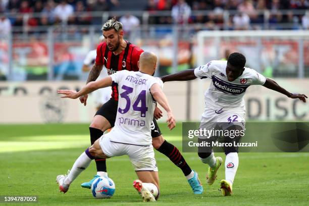 Theo Hernandez of AC Milan is challenged by Alfred Duncan and Sofyan Amrabat of Fiorentina during the Serie A match between AC Milan and ACF...