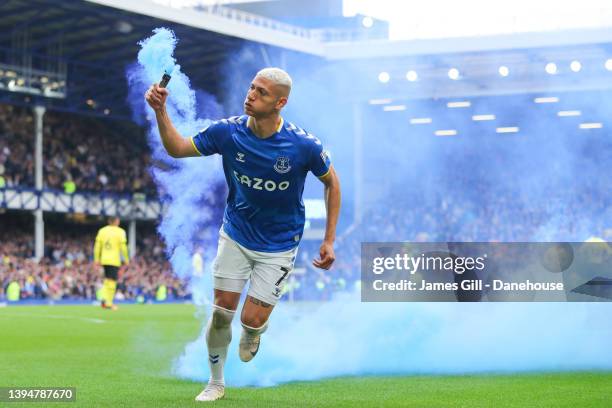 Richarlison of Everton picks up a flare as he celebrates after scoring his side's first goal during the Premier League match between Everton and...
