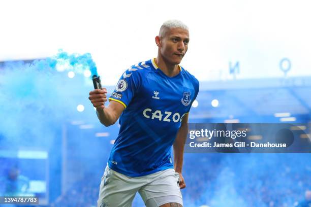 Richarlison of Everton picks up a flare as he celebrates after scoring his side's first goal during the Premier League match between Everton and...