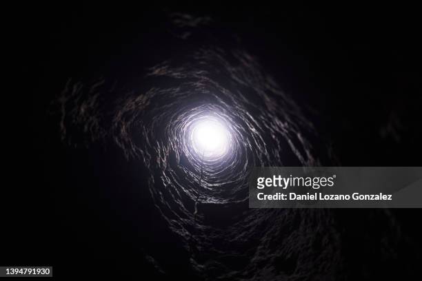 dark round tunnel with light - cave stock pictures, royalty-free photos & images