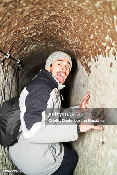 cheerful traveling man standing in aged cave city - narrow ストックフォトと画像