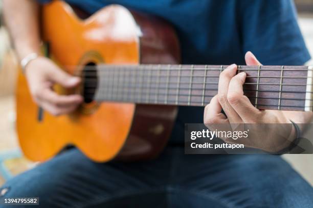 young man playing acoustic guitar at home - stock photo - stock photo - fretboard stock pictures, royalty-free photos & images