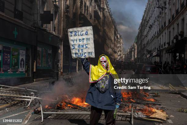 Protester holds a banner that translates as "Empty fridge! 5 more years!" at a burning barricade during a May Day march marking International...