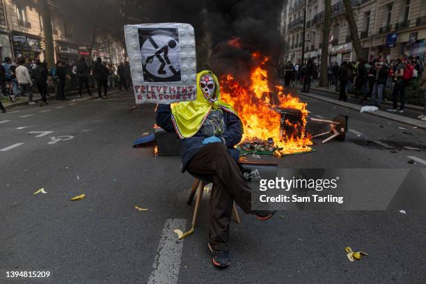 Protester holds a banner that criticises income tax at a burning barricade during a May Day march marking International Workers' Day on May 01 in...