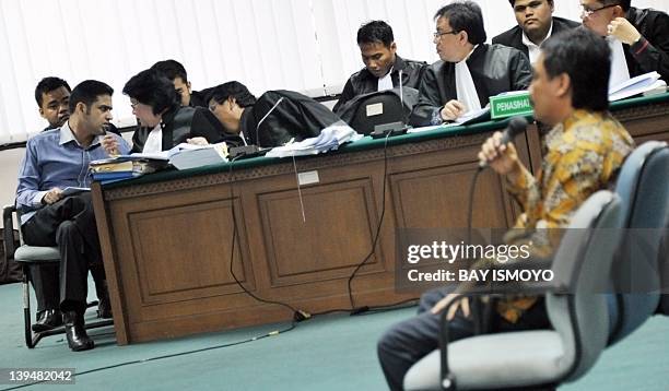 Ousted Democratic Party treasurer Muhammad Nazaruddin speaks to his lawyers during his trial while Indonesian Youth and Sports Minister Andi...