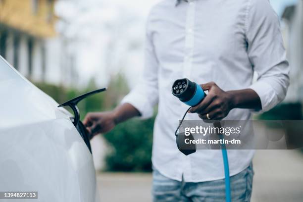 man charging electric car - opladen stockfoto's en -beelden