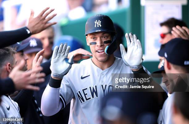 Aaron Judge of the New York Yankees is congratulated by teammates in the dugout after hitting a solo home run during the 9th inning of the game...