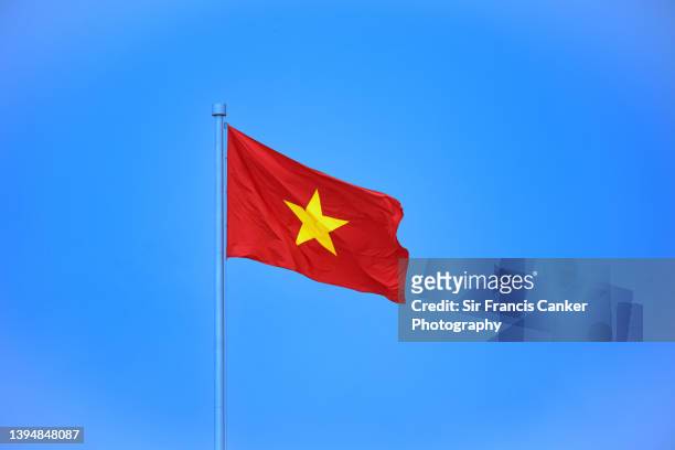 vietnamese national flag against clear blue sky in hanoi, vietnam - zuid vietnam stockfoto's en -beelden