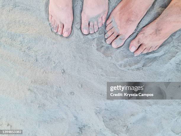 bare feet of a couple in the fine sand of a beach - mens bare feet fotografías e imágenes de stock