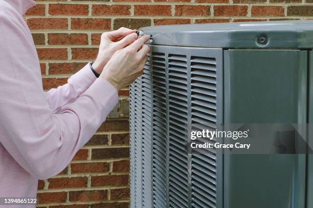 man works on air conditioner condenser unit - kondensator stock-fotos und bilder