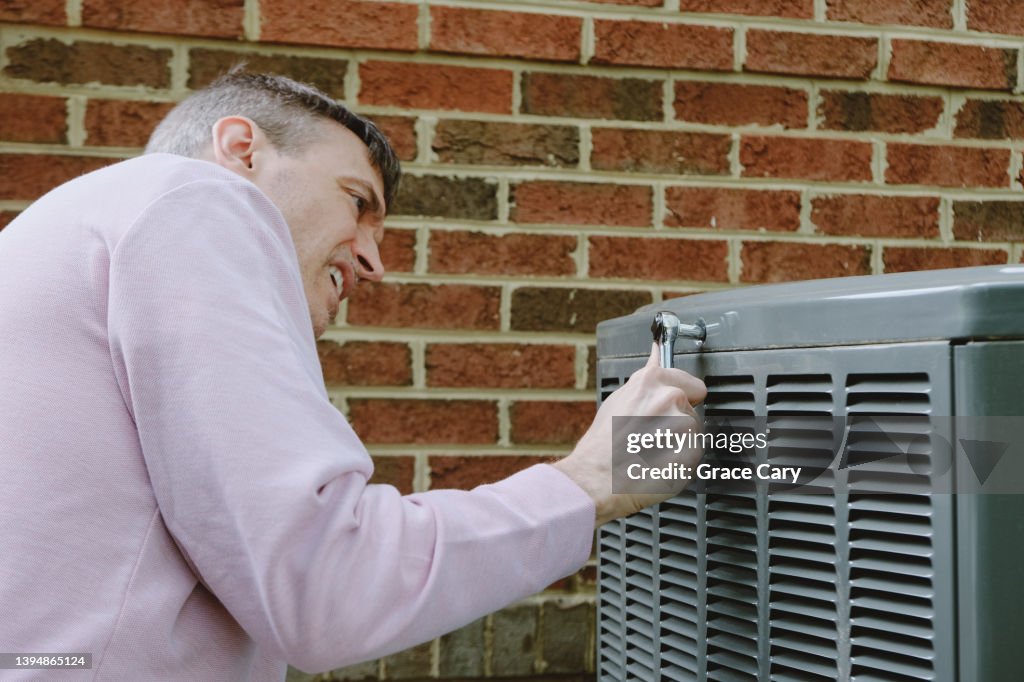 Man Works on Air Conditioner Condenser Unit
