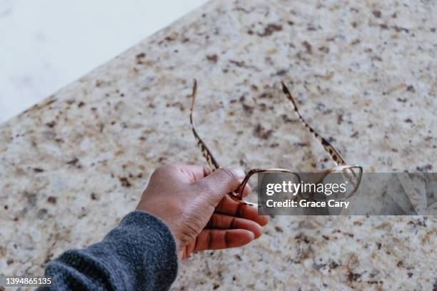 woman picks up eyeglasses from kitchen counter - reading glasses top view stock pictures, royalty-free photos & images