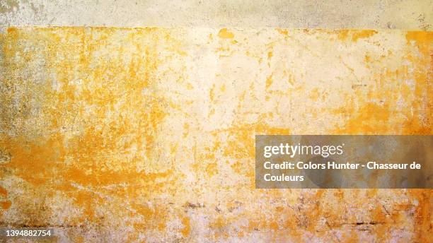 weathered and scratched yellow paint on a textured wall in paris - yellow wall stock-fotos und bilder