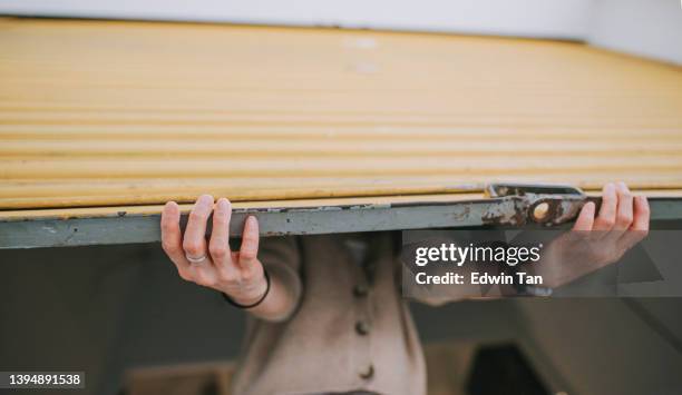 asian chinese female florist flower shop owner pushing up metal gate grill open for business - industrial doors stock pictures, royalty-free photos & images