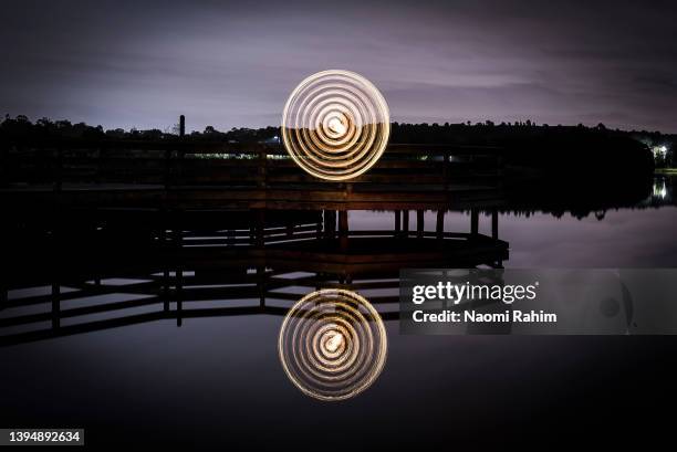 spinning lights reflecting in lake on a gloomy evening - spinnrock bildbanksfoton och bilder