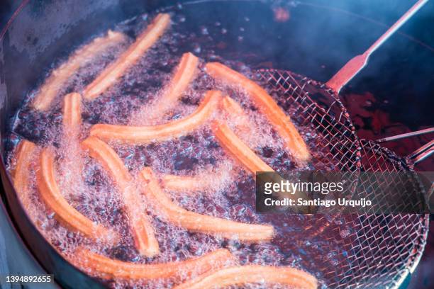 frying churros on a street market - churro stockfoto's en -beelden