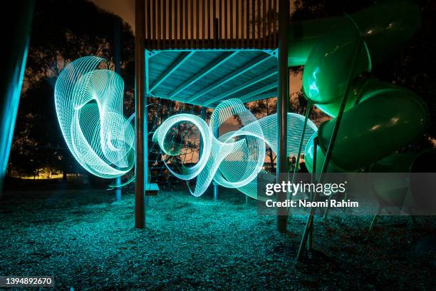 illuminated blue swirl, weaving through playground equipment at night - melbourne city at night ストックフォトと画像